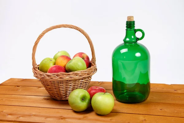 Imagen de manzanas rojas y verdes en canasta de mimbre con botella de vidrio — Foto de Stock