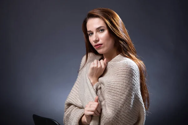 Imagen de mujer de pelo largo y rojo en jersey de punto sobre fondo oscuro — Foto de Stock