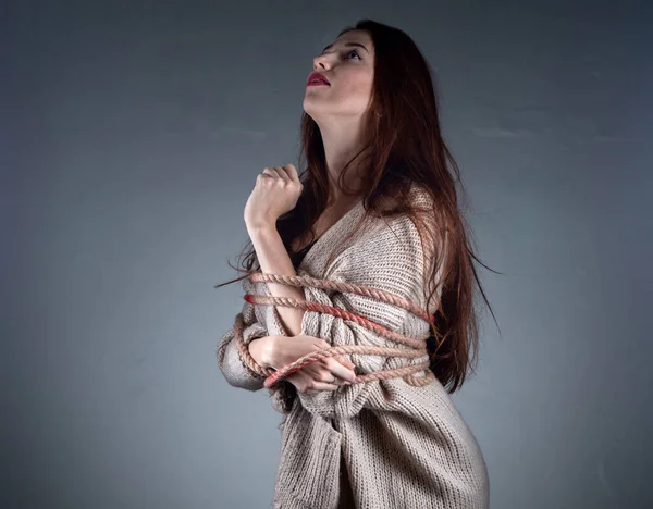 Image of young binded girl with rope on sweater on grey background — Stock Photo, Image