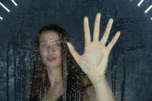 Photo de jeune fille touchant le verre avec des gouttes d'eau — Photo