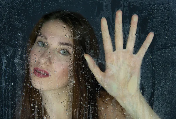 Tiro de niña tocando el vidrio con gotas de agua — Foto de Stock