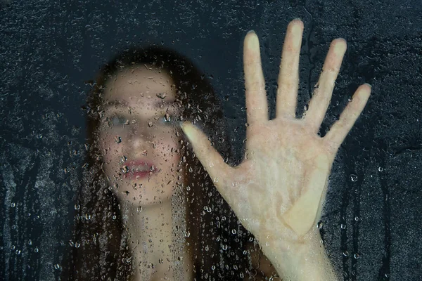 Image d'une jeune femme touchant du verre avec des gouttes d'eau — Photo