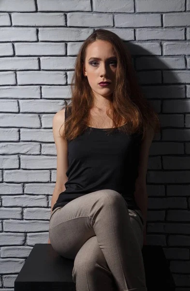 Foto der sitzenden Frau mit gekreuzten Beinen auf Backsteinmauer Hintergrund — Stockfoto