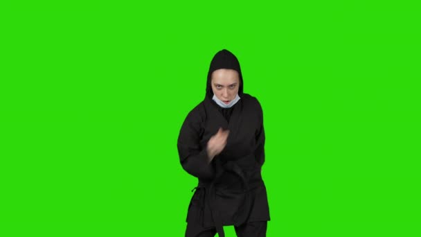 Відео жінки в чорному костюмі ніндзя одягання медичної маски — стокове відео