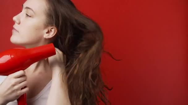 Tir de femme caucasienne séchant les cheveux longs sur fond rouge — Video