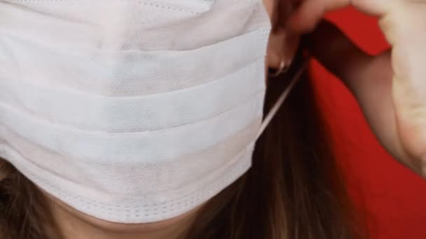 Shooting of woman dressing medical mask on red background — Stock Video