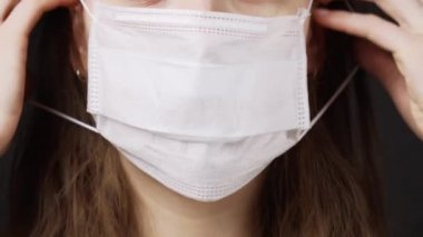 Gri arka planda tıbbi maske takan kadın.