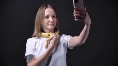 Ağır çekimde albino pitonlu bir kadın akıllı telefon tutuyor.