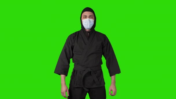 Video of struggling man in black costume ninja on green isolated background — Stock Video