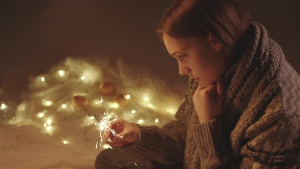 Lonely sad girl in knitted sweater with sparkler candle — Stock Video