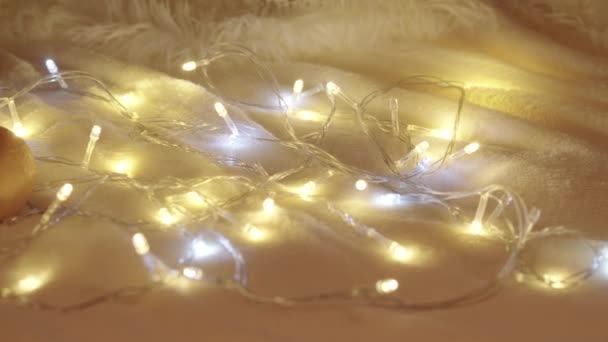 Images au ralenti de mandarines parmi les lumières de Noël sur un tapis blanc — Video