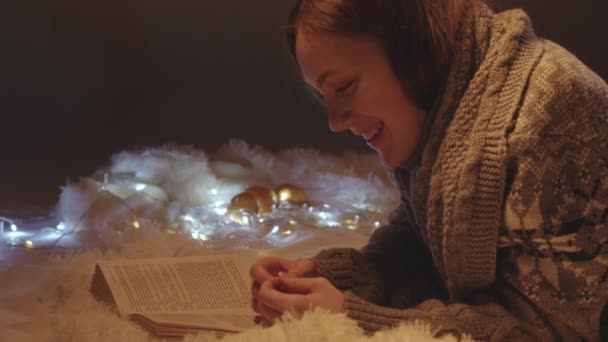 Reading girl in knitted sweater eating tangerine — Stock Video