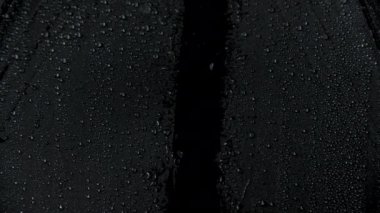 Siyah şemsiye ve su damlalarının yavaş çekim görüntüleri.