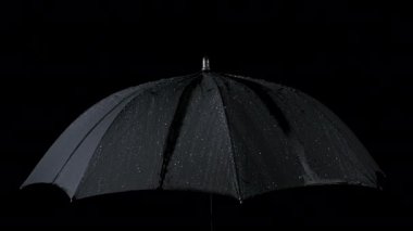 Yavaş hareket eden siyah şemsiye ve su damlaları
