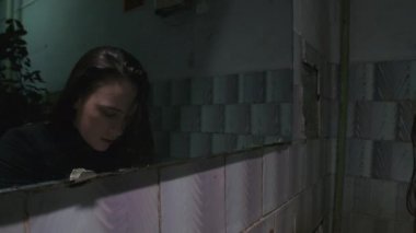 Slow motion of young woman washing face in poor bathroom