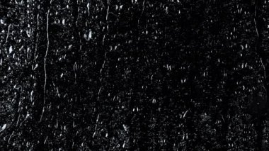 Siyah cam zemin üzerinde su damlalarının 4k yavaş çekim görüntüsü