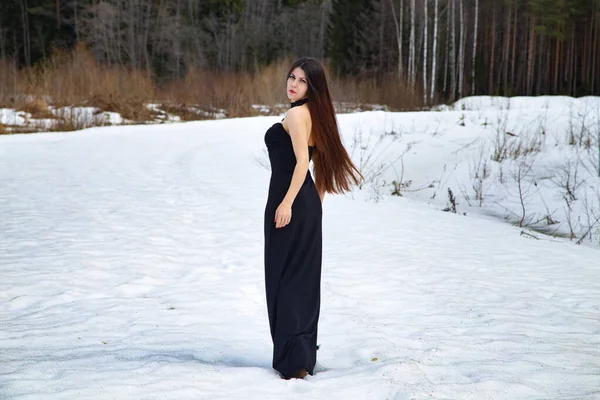 Imagen de chica caminando en un vestido negro entre la nieve — Foto de Stock