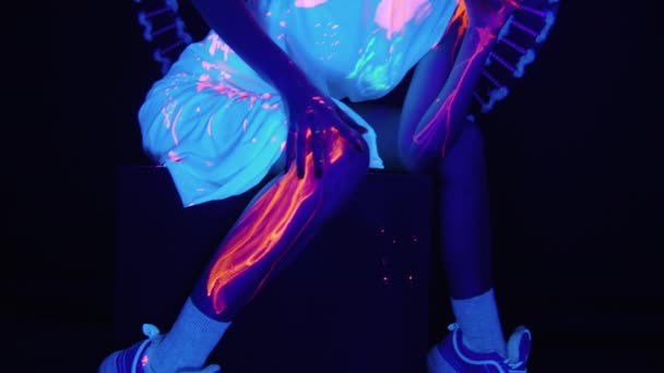 Відео жінки, що махає фарбою на нозі в ультрафіолетовому світлі — стокове відео