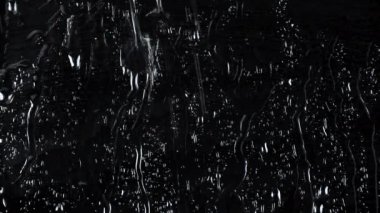 Siyah cam zemin üzerinde su damlalarının yavaş çekim 4k görüntüsü