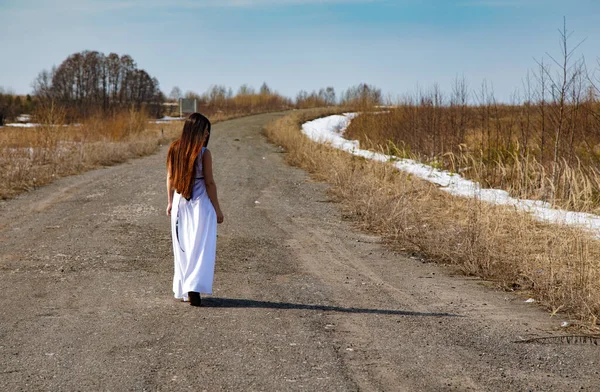 Дівчина з Брюнета у білій сукні йде по дорозі. — стокове фото