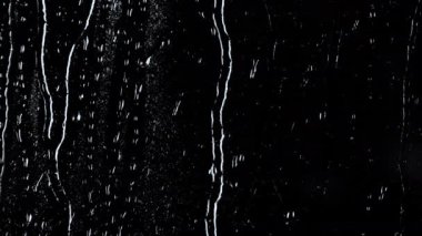 Siyah zemin üzerinde su damlalarının 4k yavaş çekim görüntüsü