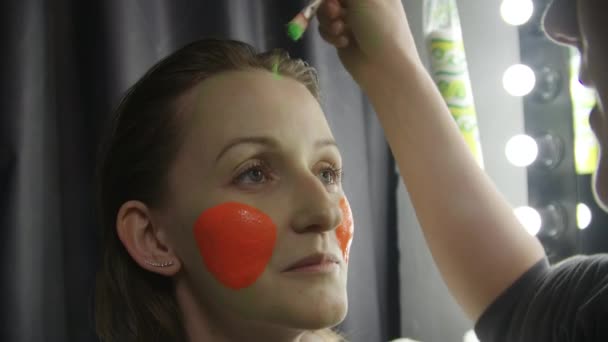 Powolny film dziewczyny nakładającej farbę na twarz modelki — Wideo stockowe
