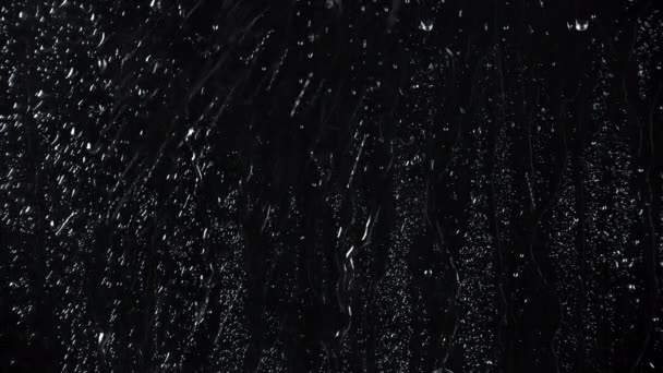 Movimiento lento de gotas de agua sobre fondo de vidrio negro — Vídeos de Stock