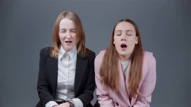 Video de dos mujeres aburridas bostezando sobre fondo gris — Vídeos de Stock