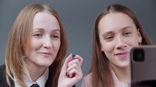 Video van twee meisjes bloggers praten met volgers op grijze achtergrond — Stockvideo