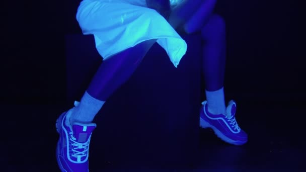 Кадри сидячої дівчини з страшним пофарбованим обличчям в ультрафіолетовому світлі — стокове відео