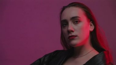 Kırmızı ve mavi ışıklı odada oturan kadının videosu.