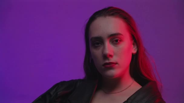 Filmagem da mulher sentada no quarto com luz vermelha e azul — Vídeo de Stock