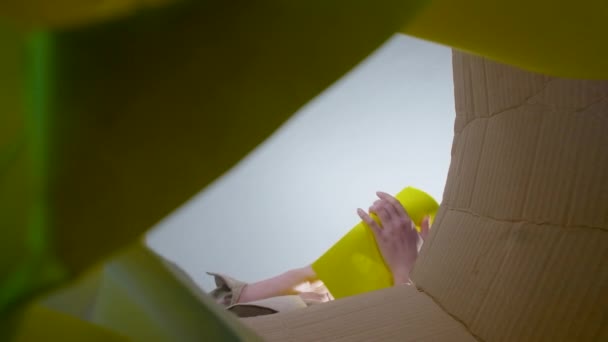 Erschießung einer Frau, die zerknittertes gelbes Papier wirft, Ansicht von unten — Stockvideo