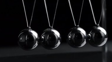 Asılı Newton toplarının siyah arkaplanda hareket halindeki videosu