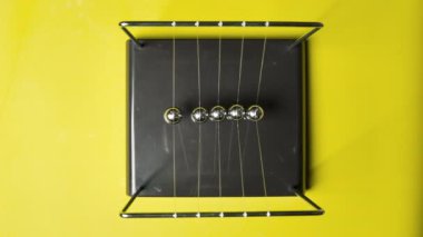 Sarı zemin üzerinde çelik Newton topları, üst görünüm