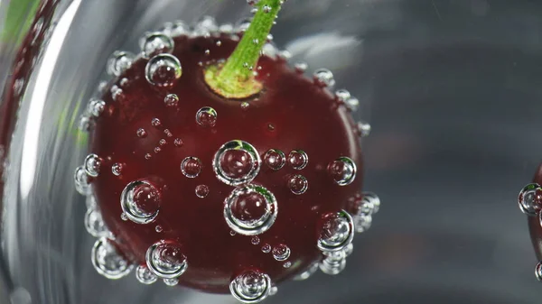 Moden kirsebær i glas med bobler af sodavand - Stock-foto