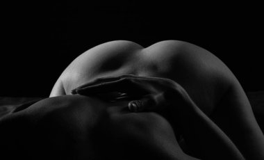 Gölgelerdeki adamın üzerinde çıplak kadın kalçalarının siyah beyaz fotoğrafı.