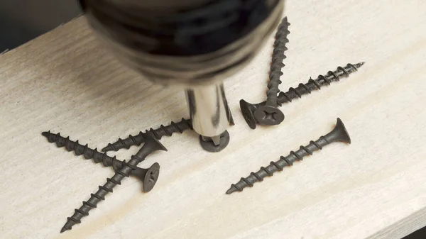 Fotografie šroubováku vrtání závitových šroubů do hrací desky — Stock fotografie