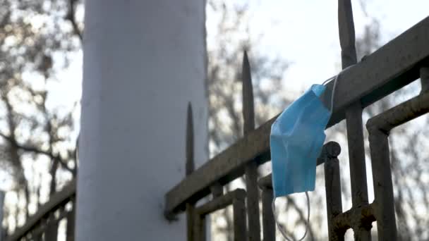 Video med begagnad medicinsk mask hängande på staketet — Stockvideo