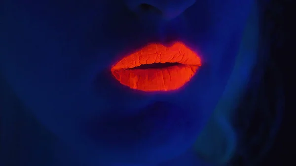 Kobieta z czerwonymi ustami pokazującymi język w świetle ultrafioletowym — Zdjęcie stockowe