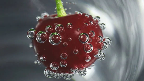 Foto de cereja em vidro com bolhas de água com gás — Fotografia de Stock