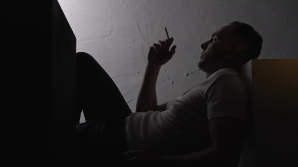Ležící závislý na kouření s cigaretou ve stínu — Stock video