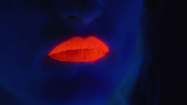 Młoda dziewczyna z czerwonymi ustami pokazuje język w świetle ultrafioletowym — Zdjęcie stockowe