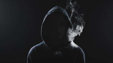 Kapüşonlu sigara içen kadının fotoğrafı.