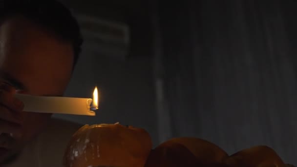 Видеозапись человека со свечой, капающей воском на сломанную куклу — стоковое видео