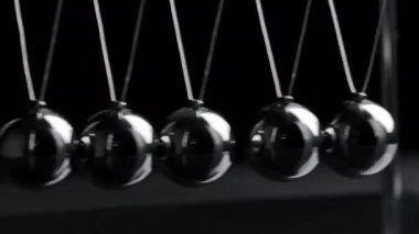 Asılı çelik Newton toplarının çekimleri siyah arkaplanda hareket halinde