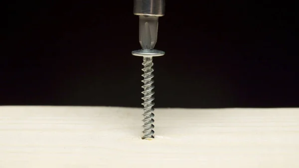 Photo of screwdriver drilling an tapping screw into wooden board — Stock Photo, Image