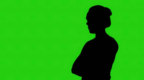 Silueta de niña con brazos cruzados sobre fondo verde — Foto de Stock