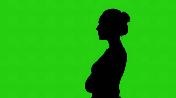 Mädchensilhouette im Profil mit verschränkten Armen auf grünem Hintergrund — Stockfoto