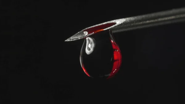 Стрельба иглой шприца с каплей красной жидкости — стоковое фото